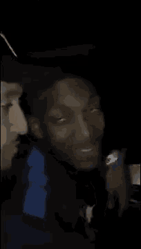 a man is making a funny face while sitting next to another man .