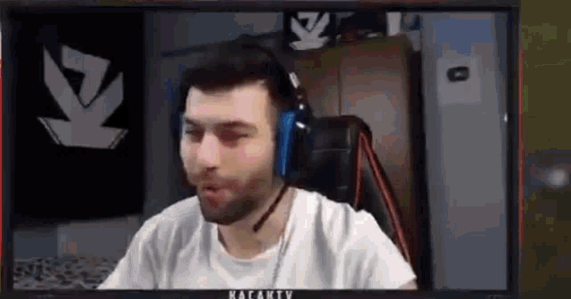 a man with a beard wearing headphones is sitting in front of a computer screen .