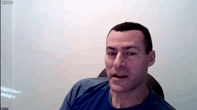 a man in a blue shirt is sitting in front of a white wall and a screen that says ' remove ' on it