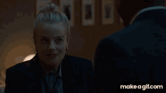a man in a suit and white shirt is talking to a woman in a room with make a gif.com at the bottom