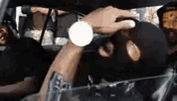 a man wearing a ski mask and a watch is sitting in the back seat of a car .