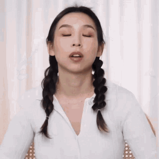 a woman with braids in her hair is wearing a white shirt and a necklace .