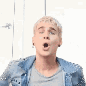a man wearing a denim jacket with studs on the sleeves blows a kiss