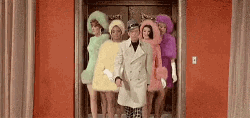 a man and three women are standing in an elevator .