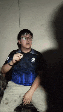 a young man wearing glasses and a blue shirt with the letter o on it
