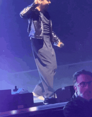 a man in a leather jacket singing into a microphone