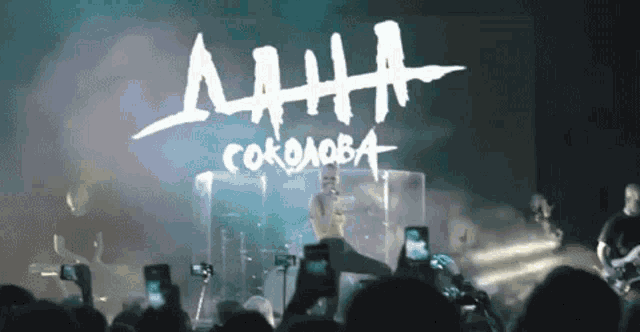 a man singing into a microphone in front of a sign that says anna cokolova