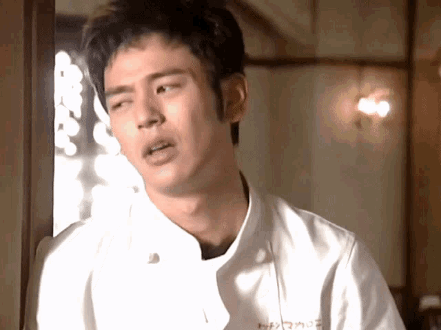 a man wearing a white chef 's jacket with chinese writing on the front