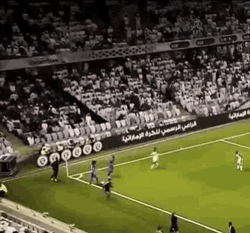 a soccer game is being played in a stadium with arabic writing on the sidelines