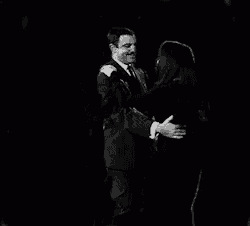 a black and white photo of a man and a woman dancing in the dark .