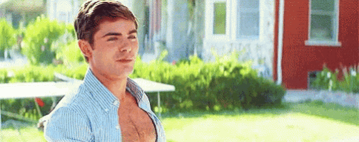 a man is standing in front of a red house with his shirt off .
