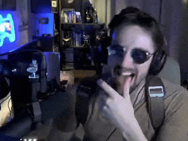 a man wearing sunglasses and headphones is making a funny face while sitting in front of a computer .