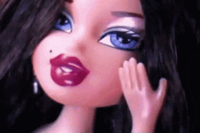 a close up of a doll 's face with a hand on her face .