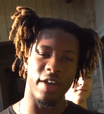 a young man with dreadlocks looks at the camera