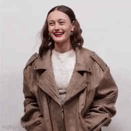 the woman is wearing a brown leather jacket and smiling .