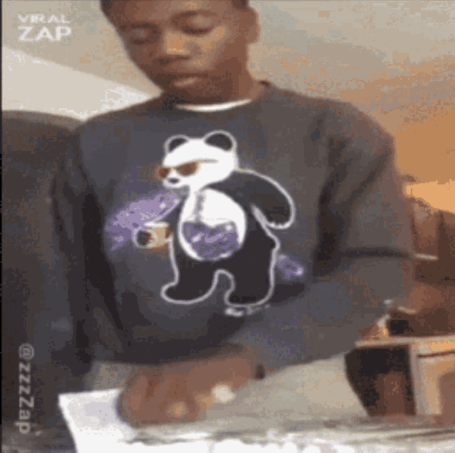 a man wearing a sweater with a panda bear on it is holding a piece of paper