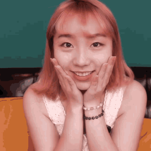 a woman with pink hair and a bracelet on her wrist smiles