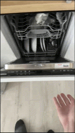 a person 's hand is reaching into a dishwasher filled with dirty dishes
