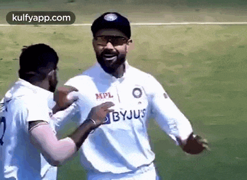 a couple of men are hugging each other on a field .