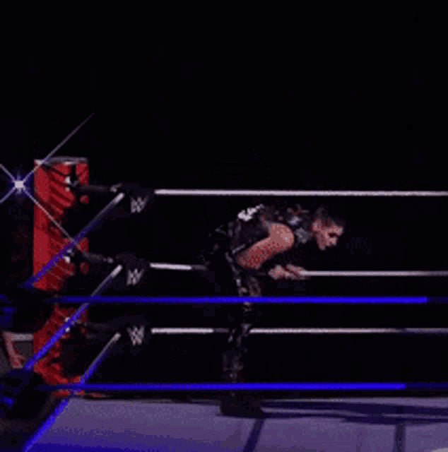 a wrestler is standing in a wrestling ring with the letter w on the ring