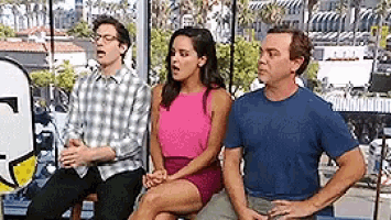 a group of people are sitting next to each other on a bench in front of a window .