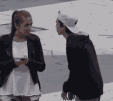 a man and a woman are standing next to each other and the woman is holding a cell phone .