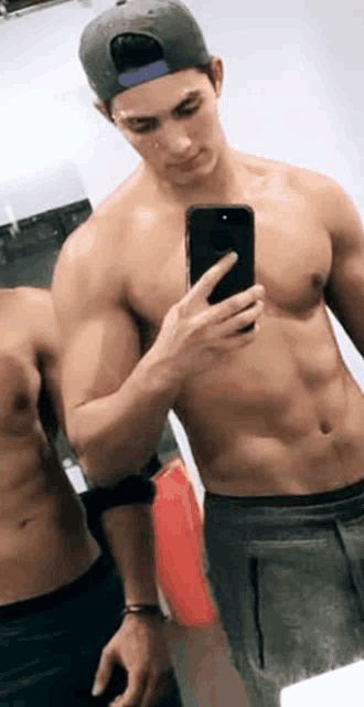 a shirtless man is taking a picture of himself in the mirror