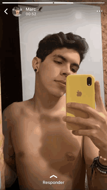 a shirtless man is taking a selfie with a yellow apple phone