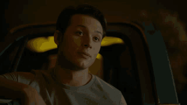 a man in a grey shirt is sitting in a car