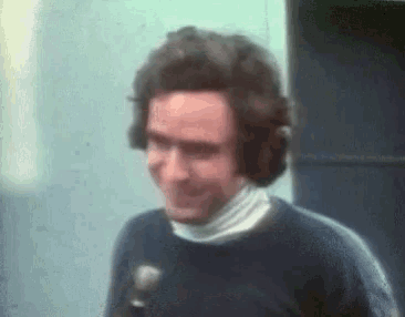 a man wearing headphones and a white turtleneck is standing in front of a microphone
