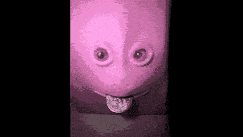 a green and a pink urinal with a tongue sticking out in a bathroom .