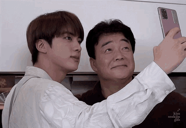 a man taking a selfie with another man with kim seokjin gifs written on the bottom