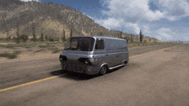 a silver van is driving down a highway with mountains in the background