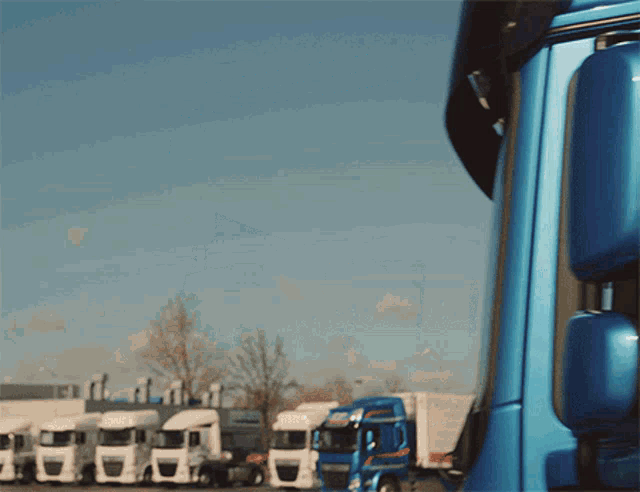 a row of trucks are parked in a parking lot with a sign that says ' dhl ' on it