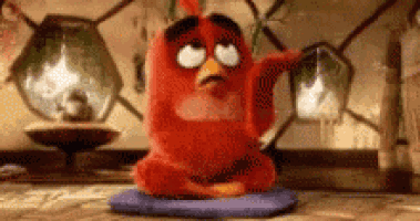 a red angry bird is sitting on a blue cushion on the floor .