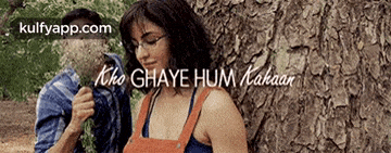 a man and a woman are leaning against a tree with the words " kho ghaye hum kakaar " written above them