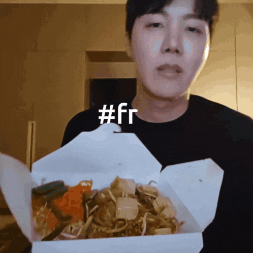 a man in a black shirt is holding a box of food with the hashtag #fr above his head