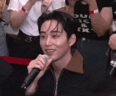 a man is holding a microphone in front of a crowd .