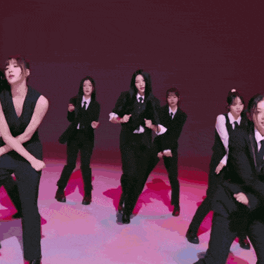 a group of women in black suits and ties are dancing on a pink background
