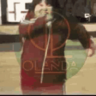 a woman in a red jacket is standing on a basketball court holding a hoop .