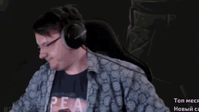a man wearing headphones is sitting in a chair with the word top on the bottom left
