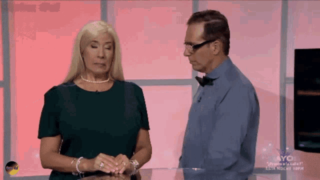 a man and a woman are standing next to each other in front of a screen that says ayo