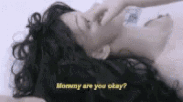 a woman is laying on her stomach with her eyes closed and a bottle in her hand .