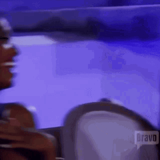 a woman is sitting in a chair with a purple background and talking to another woman .