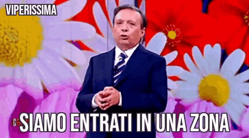 a man in a suit and tie stands in front of flowers and says siamo entrati in una zona