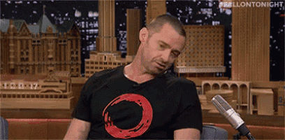 a man is sitting in front of a microphone wearing a black t-shirt with a red circle on it .