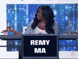 a woman is sitting at a table with a sign that says remy ma on it