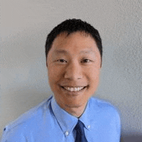 a man in a blue shirt and tie is smiling .