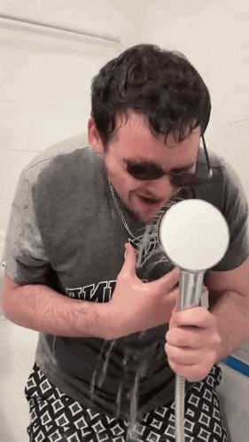 a man wearing a star wars shirt is holding a shower head in front of his face