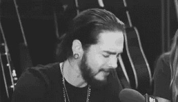 a man with a beard is sitting in front of a microphone and crying .